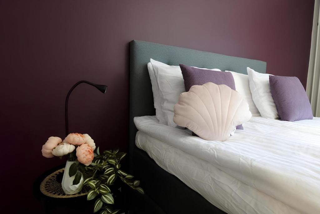 um quarto com uma cama com lençóis brancos e almofadas roxas em Spacious Haven near Mall and Convention Center em Helsinque