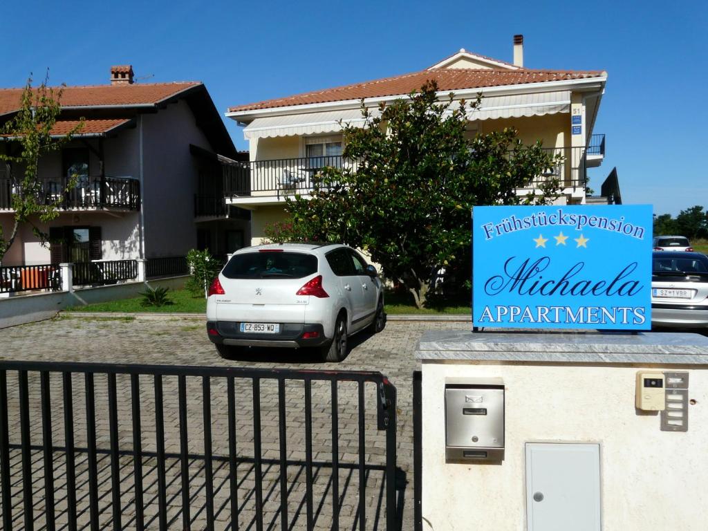 un coche blanco aparcado en un aparcamiento al lado de un edificio en Apartments and Rooms Michaela, en Fažana