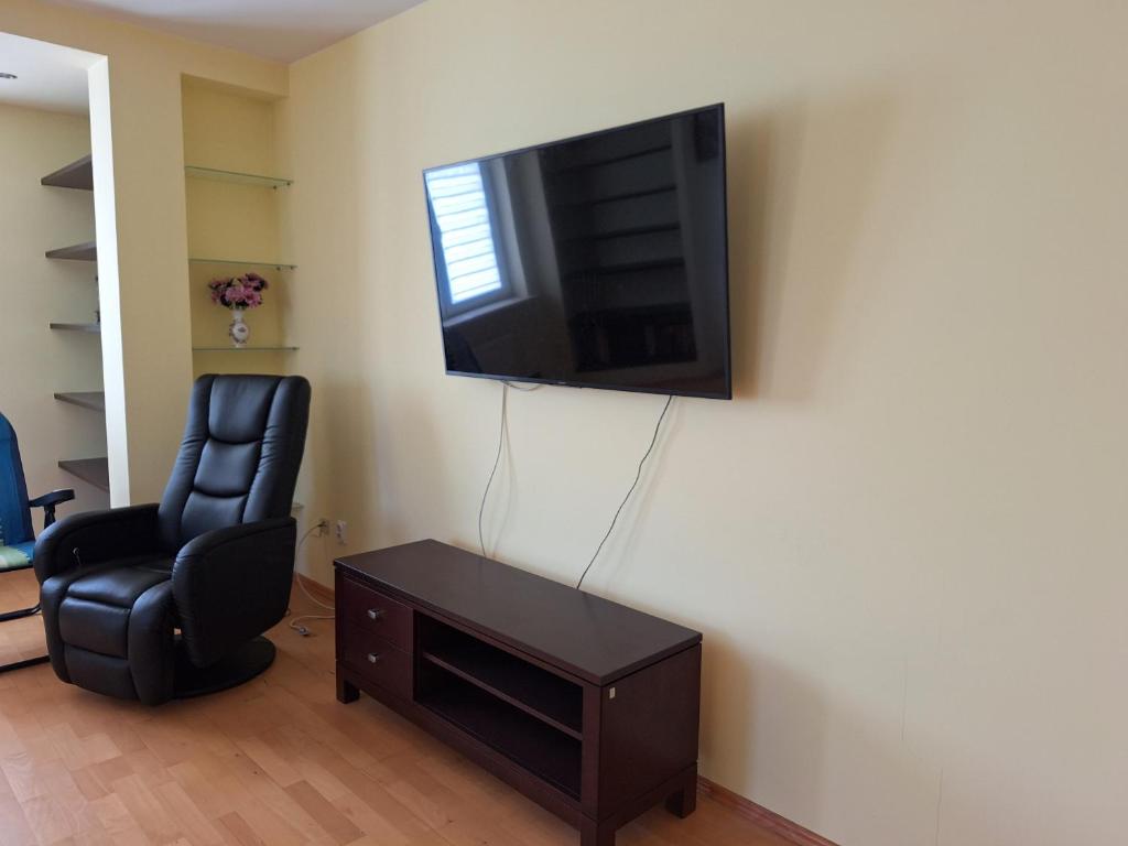 uma sala de estar com uma cadeira e uma televisão na parede em Apartament Rose Stalowa Wola em Stalowa Wola