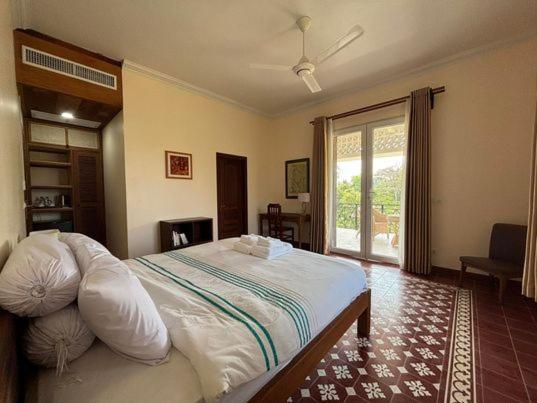 a bedroom with a large bed and a window at La maison bleue BTB in Phumĭ Kâmpóng Âmpĭl