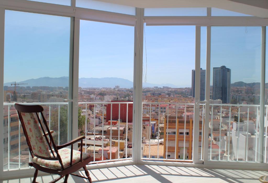 a chair sitting on a balcony with a view of a city at Rare find! Skyline view-Modern 6 bed 2 bath flat in the heart of Málaga in Málaga