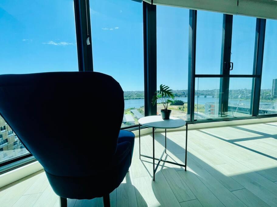 una silla y una mesa frente a una gran ventana en Fascinating waterview 2 bedrooms condo (Parking), en Sídney