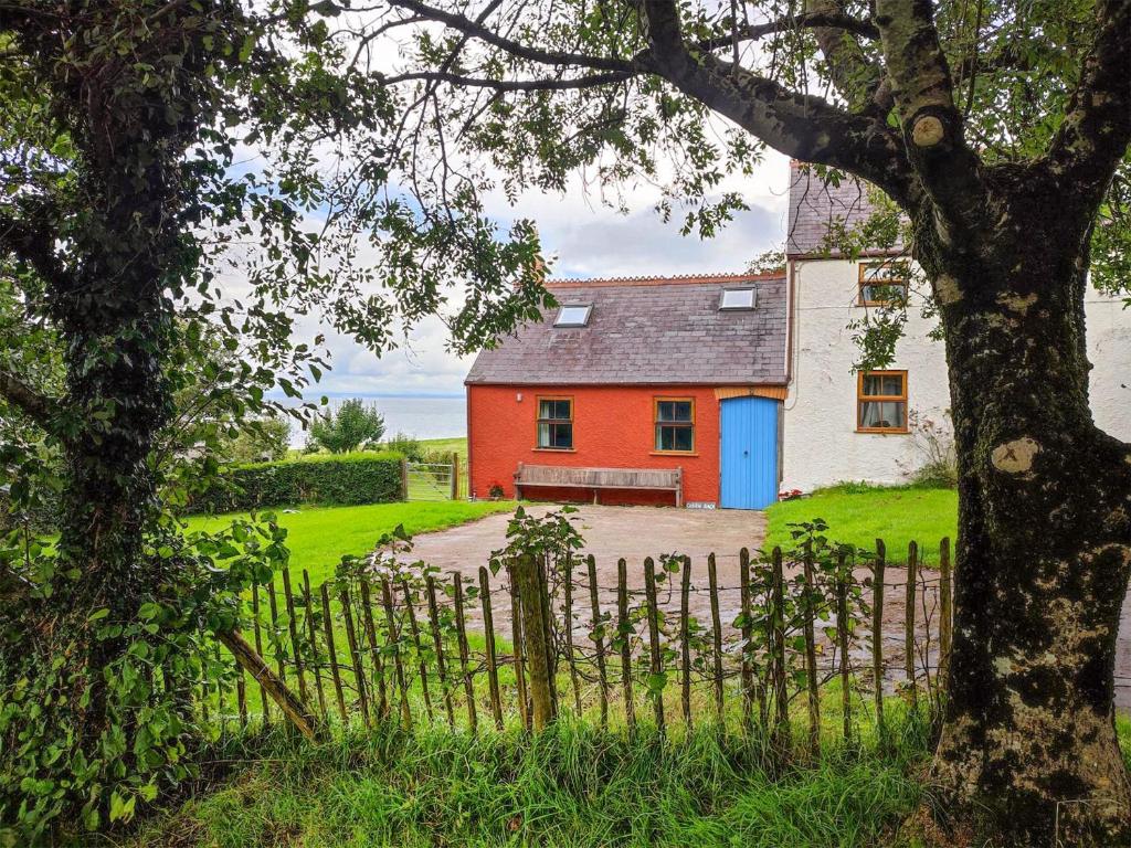 a red and white house with a blue door at Ceiliog Bach in Llangennith