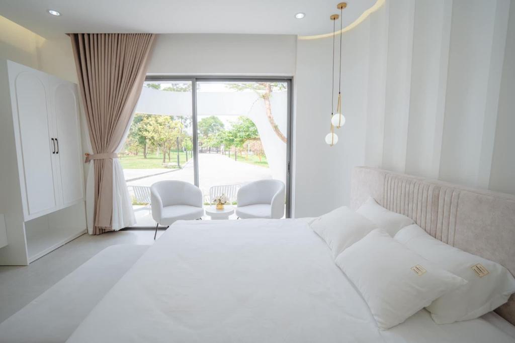 順化的住宿－Jade Hill Villa，白色卧室配有一张大床和两把椅子