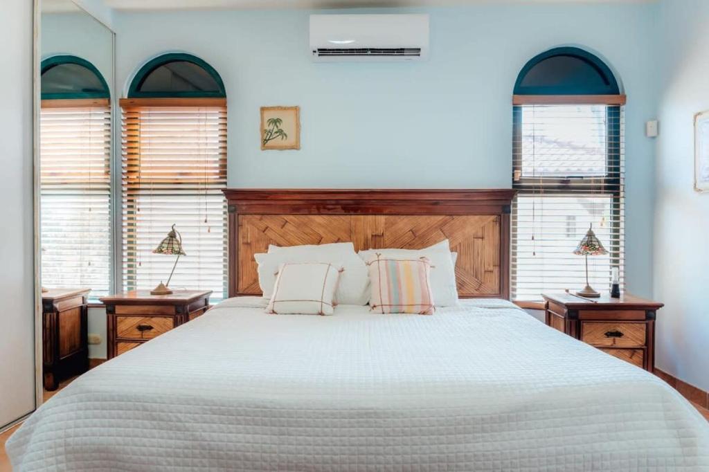 a bedroom with a large bed with white sheets and windows at The elegance of Tierra del Sol with private pool in Palm-Eagle Beach