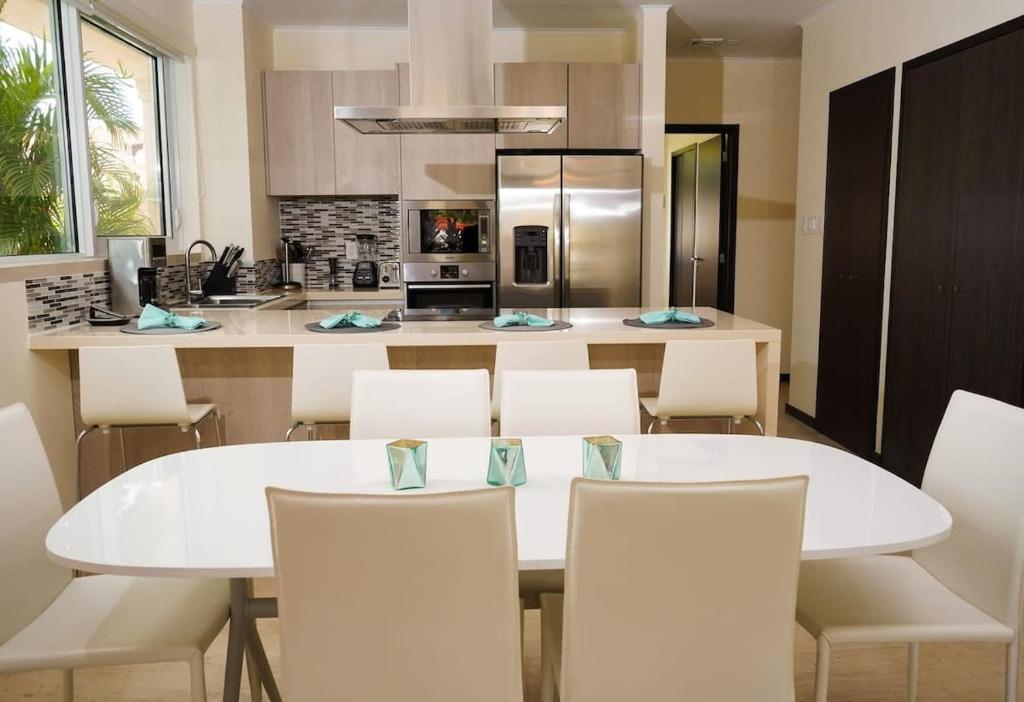 uma cozinha com uma mesa branca e cadeiras brancas em Spectacular apartment in levent eagle beach em Palm-Eagle Beach