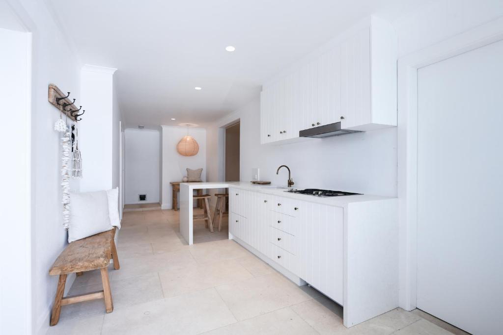 cocina blanca con mesa y silla en Hamptons style Warriewood Beachhouse, en Mona Vale