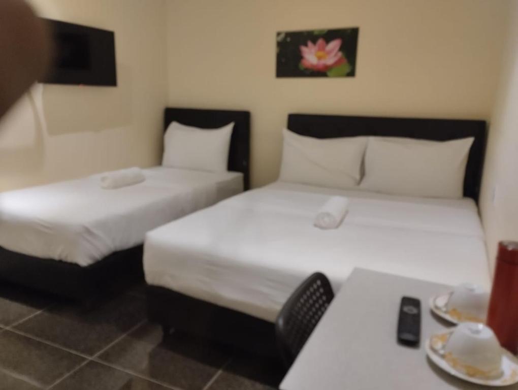 two beds in a room with a table with plates of food at I Go Inn in Bandar Saujana Putra