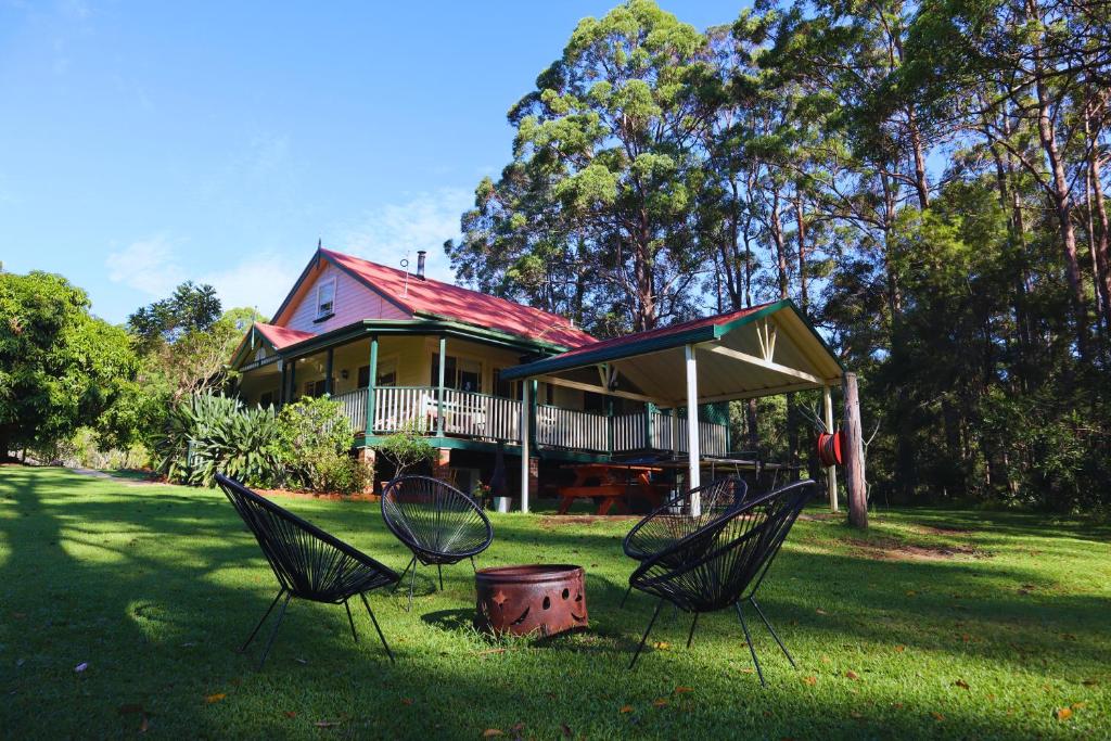 a house with three chairs in the grass in front of it at Telegraph Retreat Cottages in Telegraph Point