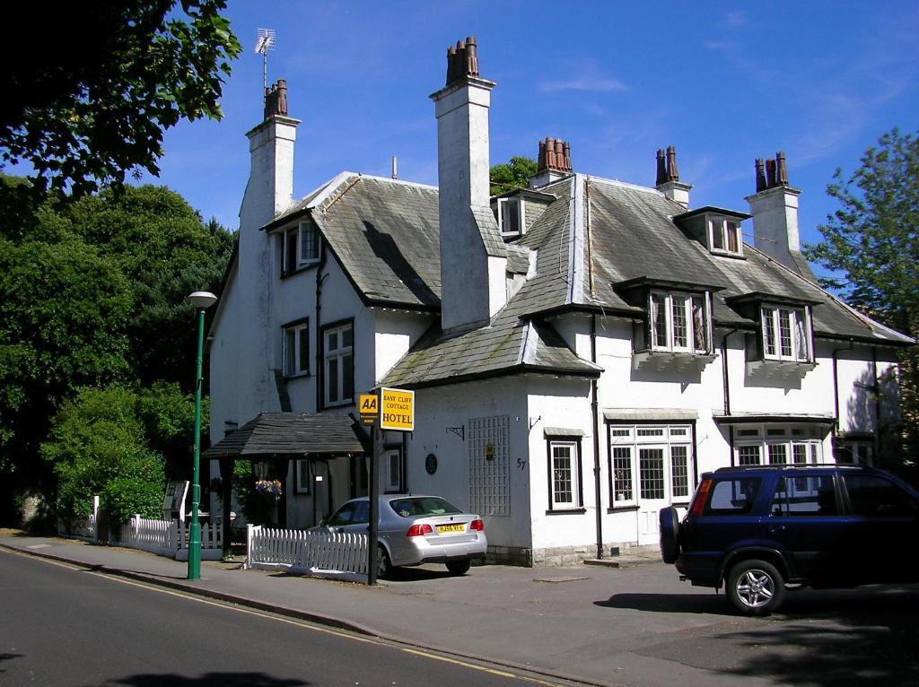 una casa blanca con un coche aparcado delante de ella en East Cliff Cottage Hotel, en Bournemouth