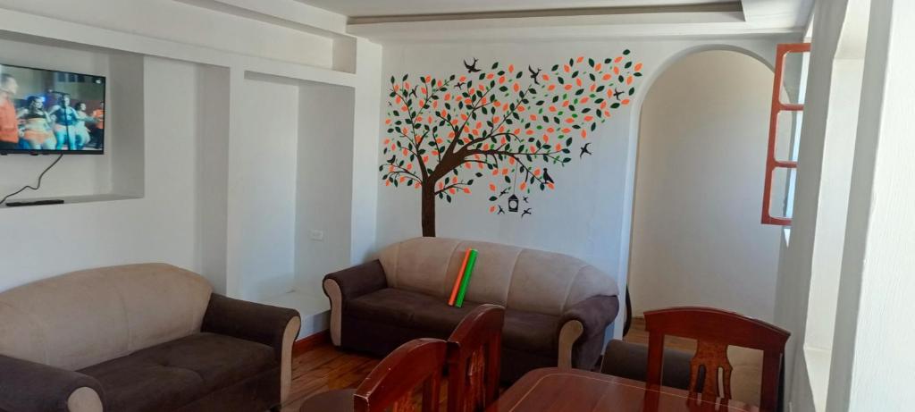 a living room with a tree painted on the wall at Departamento Riobamba in Riobamba