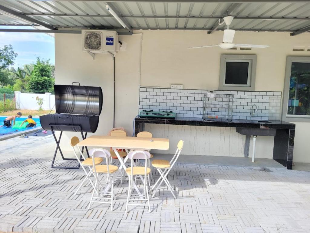 a patio with a table and chairs and a grill at MyKampung Homestay in Rembau