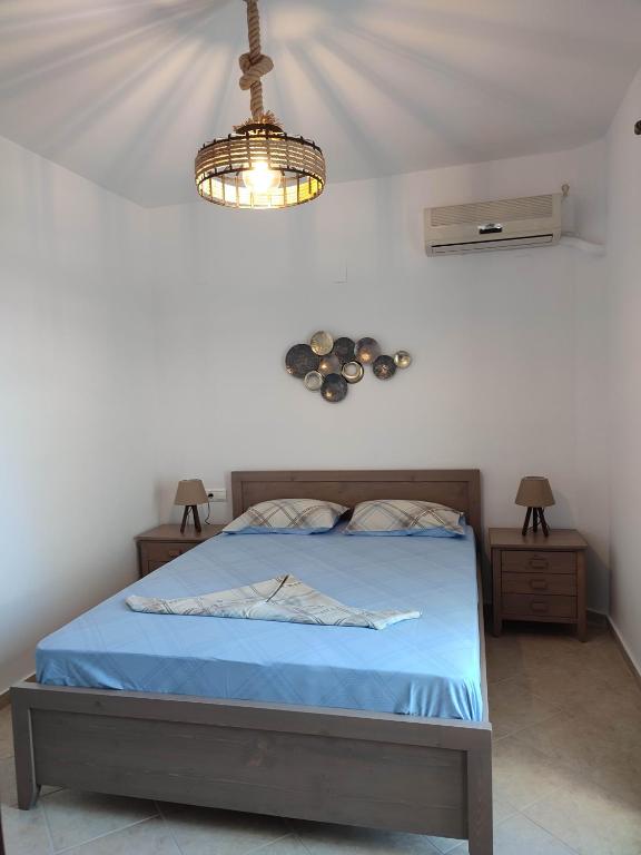 a bedroom with a bed with blue sheets and a chandelier at ANATOLI ROOMS SERIFOS in Serifos Chora