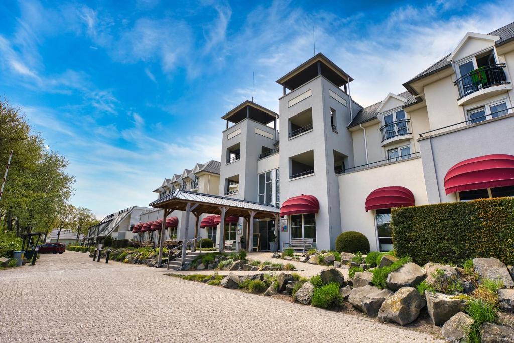 een groot wit gebouw met rode luifels bij Hotel De Zeeuwse Stromen in Renesse