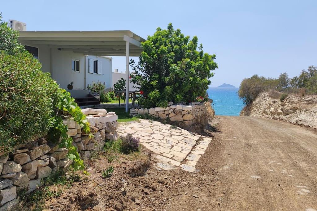 ein Haus mit einer Steinmauer neben einer Straße in der Unterkunft Bungalow Thalassa, am Strand und mit Mini-Pool in Kalamaki
