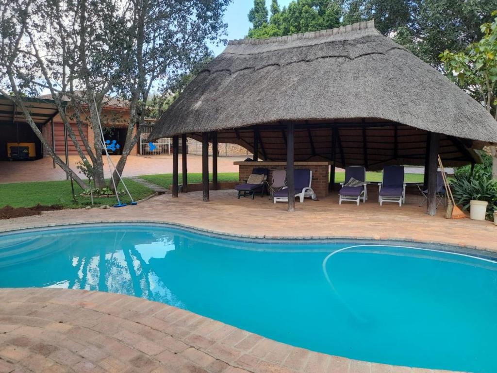 Cabaña con sillas y piscina en The Villa, en Bulawayo