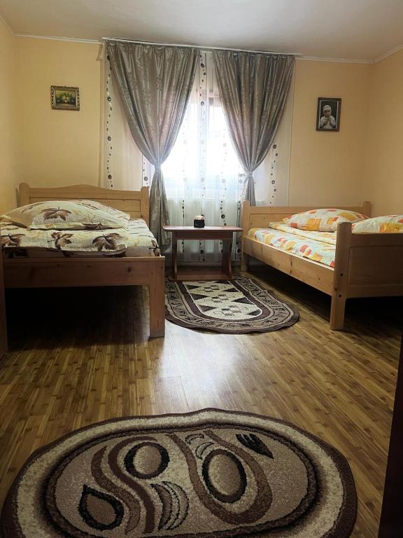 two beds in a room with a window and a rug at Casa Ghețari in Gheţari
