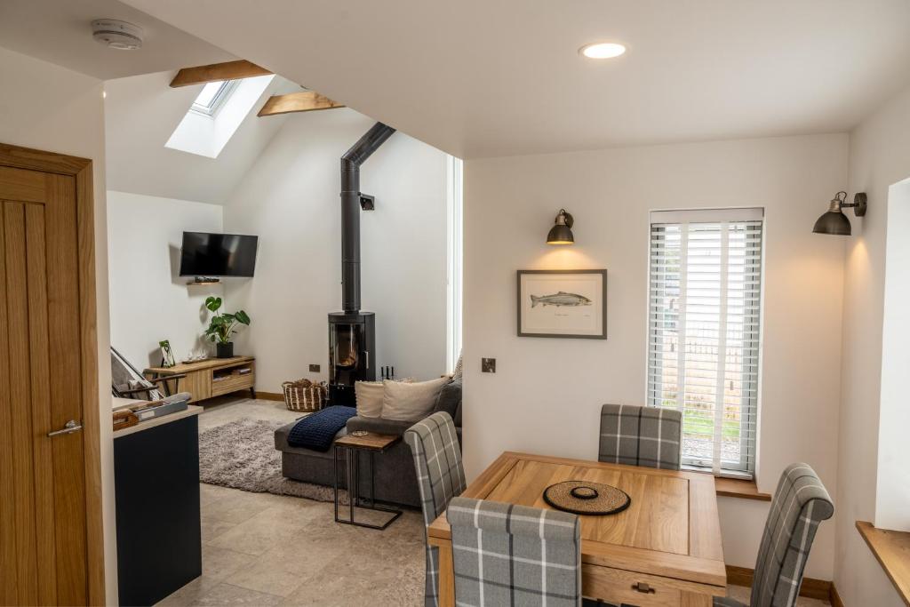 a living room with a table and a kitchen at Nana Cottage , Findhorn Village in Findhorn