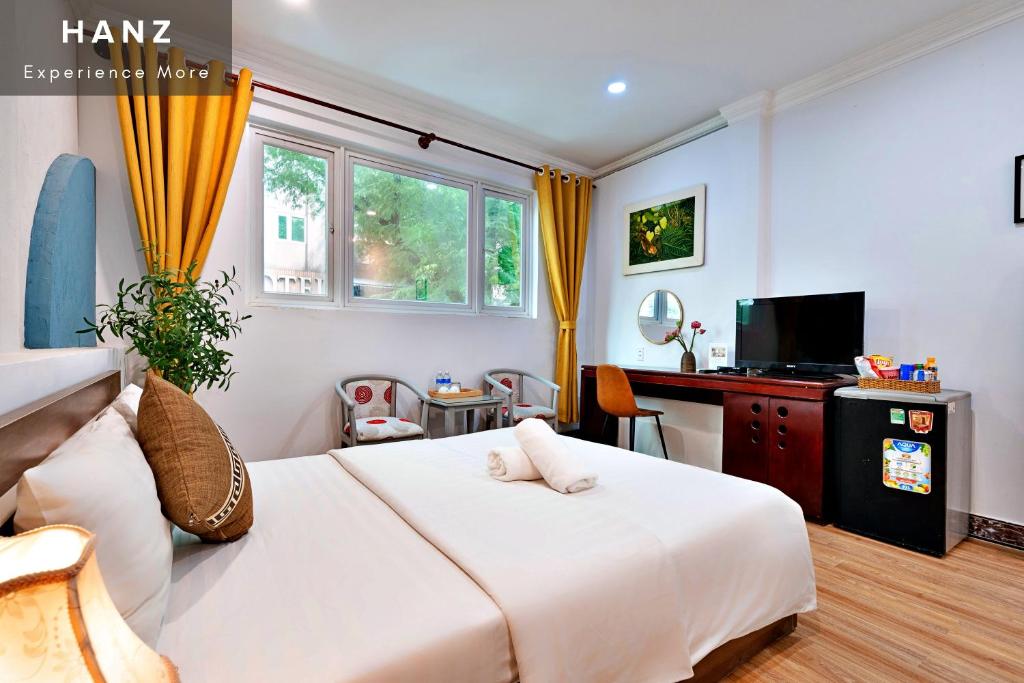 a bedroom with a large white bed and a desk at HANZ Cosmo Central Hotel Ben Thanh in Ho Chi Minh City