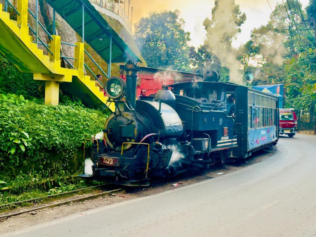 un vieux train à vapeur circulant sur les voies dans l'établissement Hotel Lee Green- best family hotel in Darjeeling, à Darjeeling