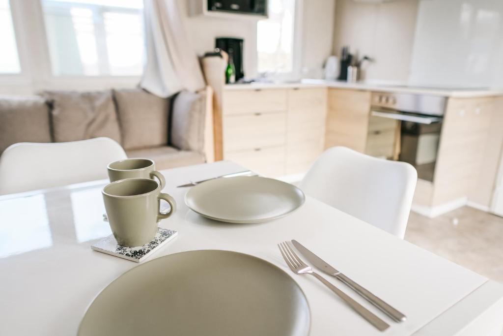 a white table with two plates and cups on it at Magnolia - Camping Belle-Vue in Berdorf