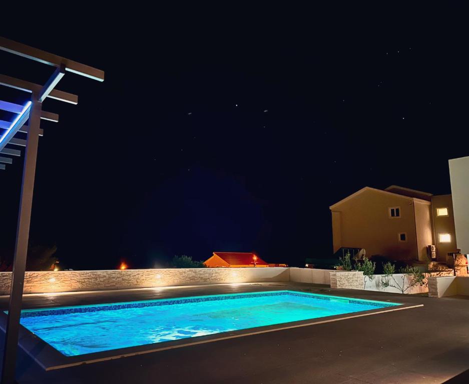 a swimming pool in a backyard at night at Apartments ŽAJA in Seget Vranjica
