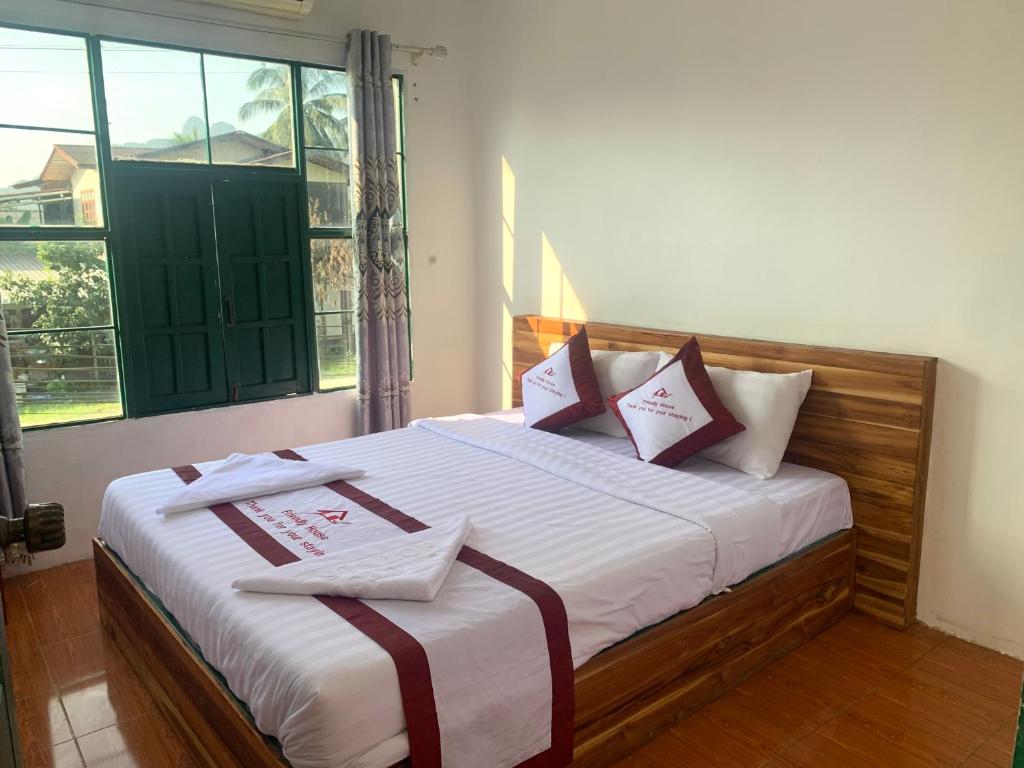 Vang Vieng Lily Guesthouse في فانغ فينغ: غرفة نوم بسرير كبير ومخدات حمراء وبيضاء