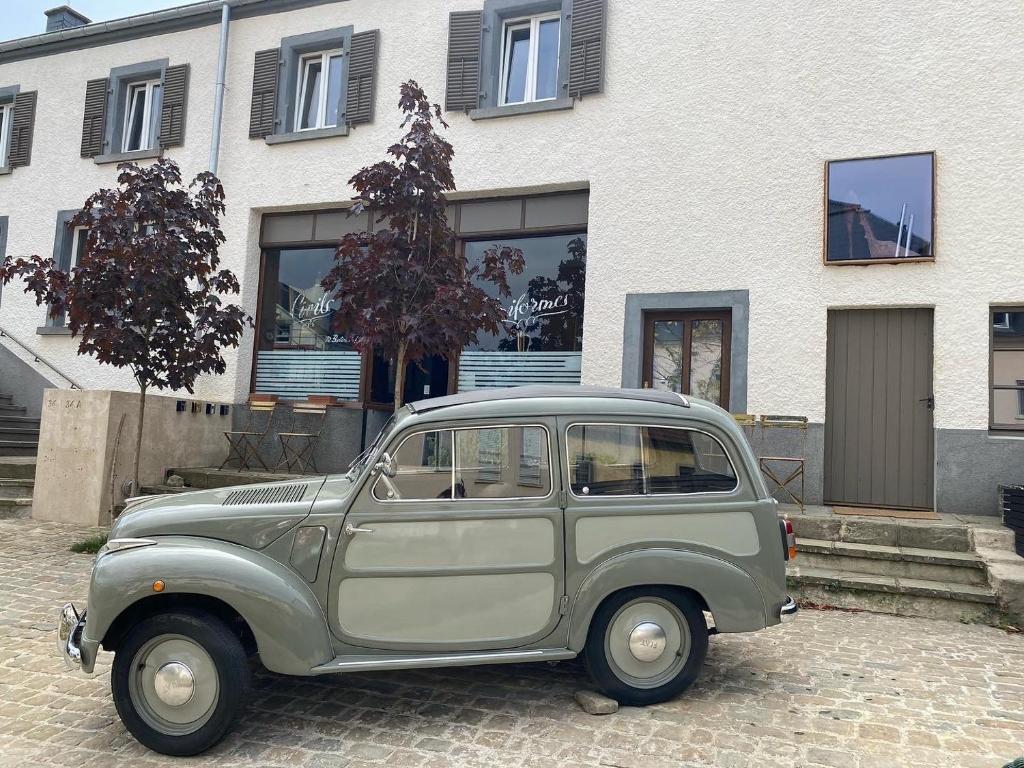 ein altes grünes Auto, das vor einem Gebäude parkt in der Unterkunft Tailor's Trail gîte d'adventure Beaufort Mullerthal in Befort