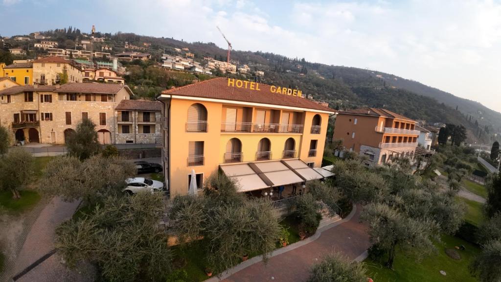 un bâtiment jaune avec un centre hôtelier sur une colline dans l'établissement Hotel Garden, à Torri del Benaco