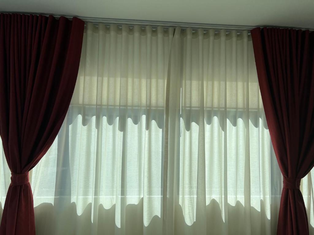 Luxury accommodation في سيدني: نافذة ذات ستائر بيضاء وستائر حمراء
