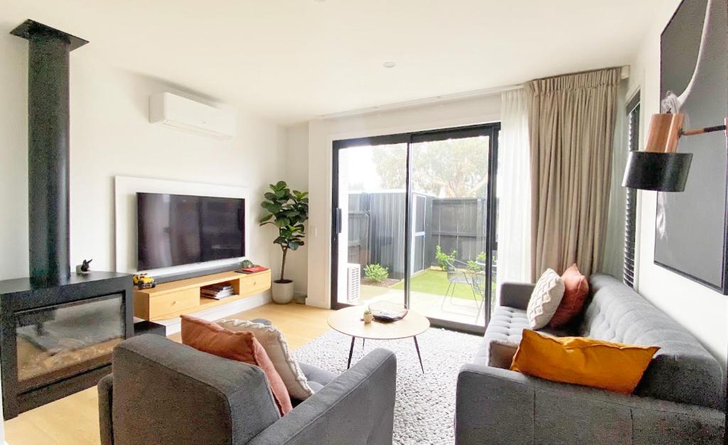 uma sala de estar com dois sofás e uma televisão em Burrows Hutch Wanaka em Albert Town