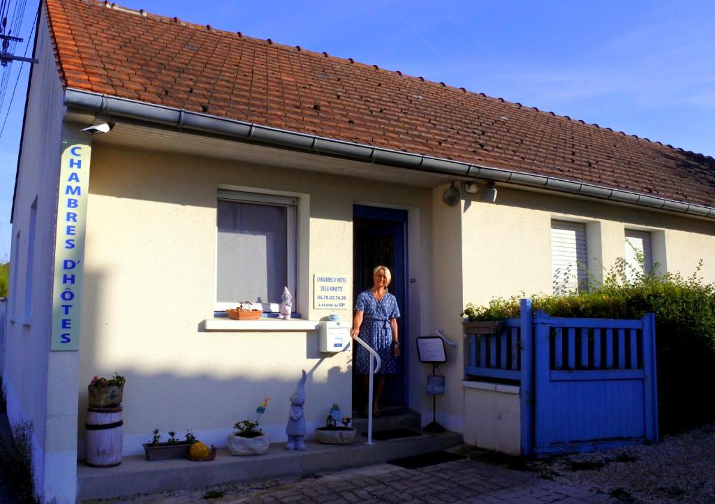 une femme debout à l'entrée d'une petite maison dans l'établissement chambres de la Nonette, à Senlis