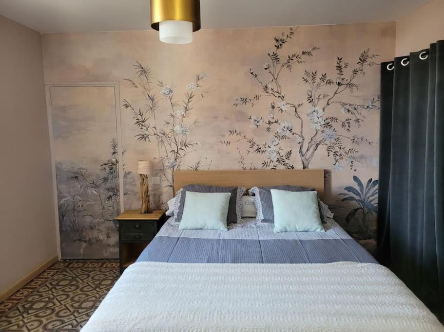 een slaapkamer met een bed en een muur met bloemen bij Maison de village panoramique in Châteauneuf-du-Pape