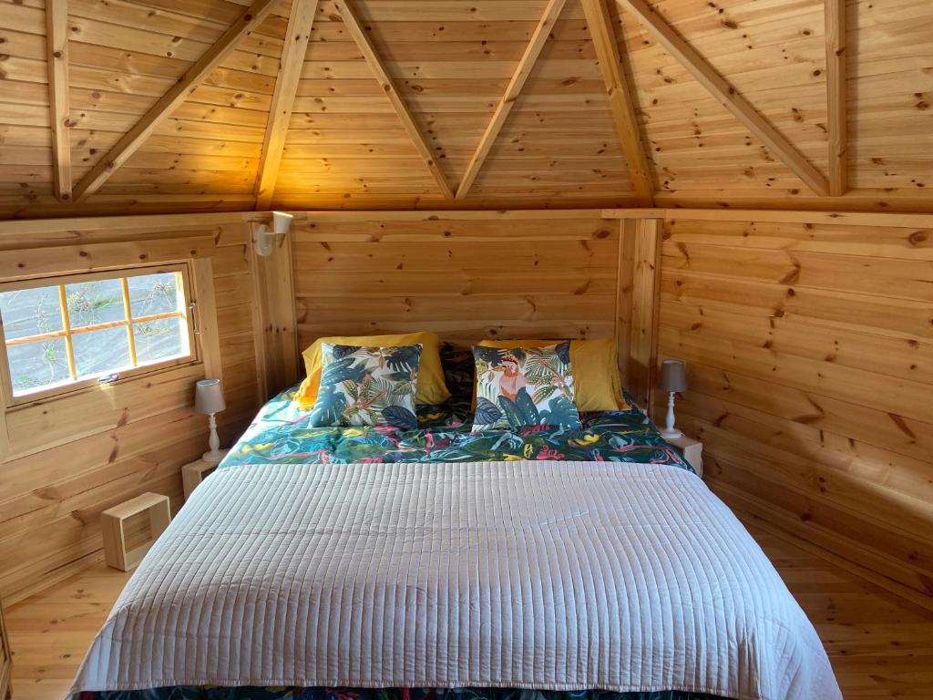 Maison bois kota / bain nordique / proche de la mer / kota grill في Longueil: غرفة نوم في كابينة خشب بها سرير