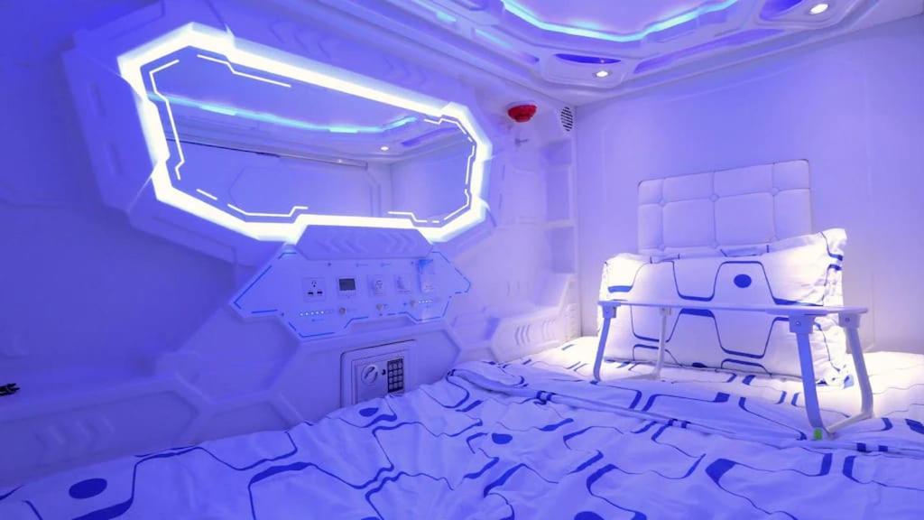 een kamer met een bed in een kamer met blauwe verlichting bij V Space CAPSULE CAFE MELAKA in Melaka