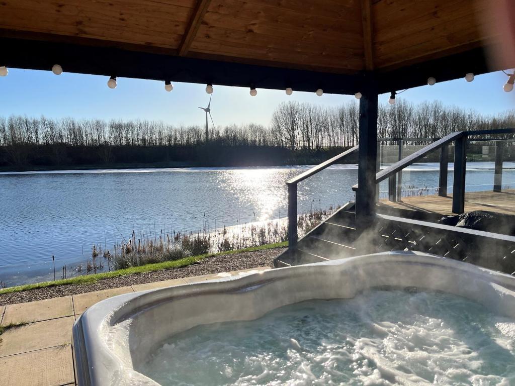 a hot tub with a view of the water at Waterside Retreat Heron Lakes Nr Beverley in Beverley
