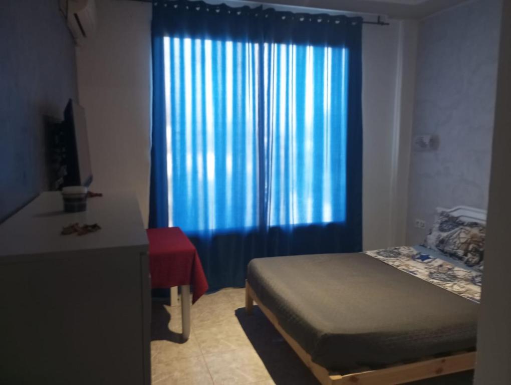 - une chambre avec un lit et un rideau bleu dans l'établissement VILLA BELLA VITA HAMMAMET, à Hammamet Sud