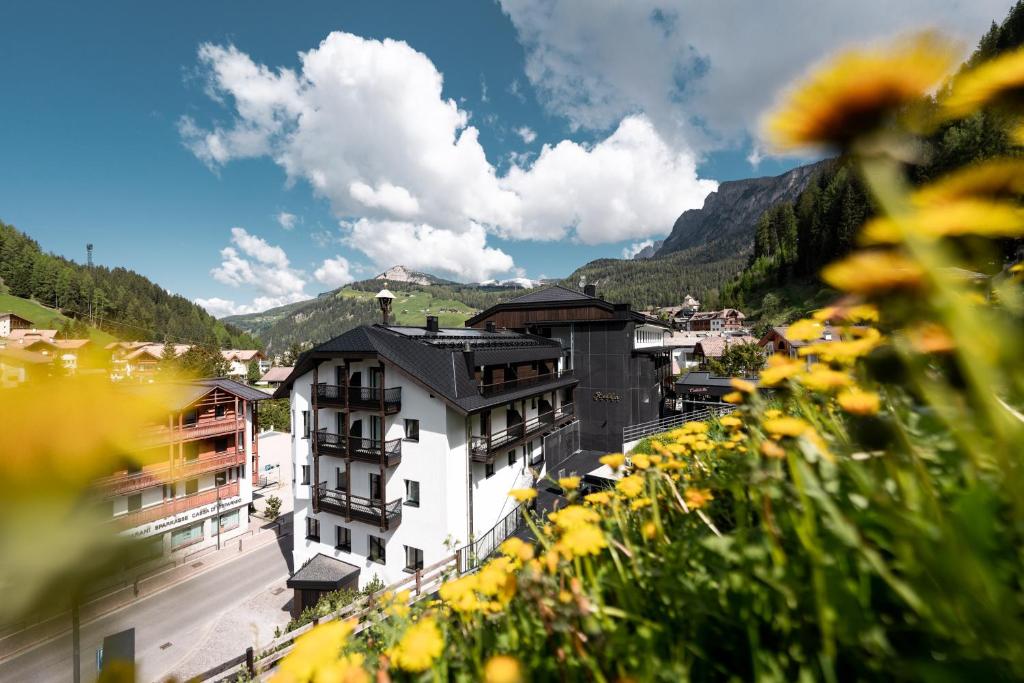 a view of a town in the mountains with yellow flowers at Stella Hotel - My Dolomites Experience in Selva di Val Gardena