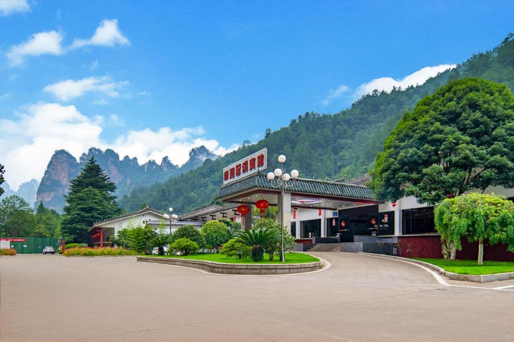 a building in front of a mountain with trees at Hunan New Pipaxi Hotel in Zhangjiajie