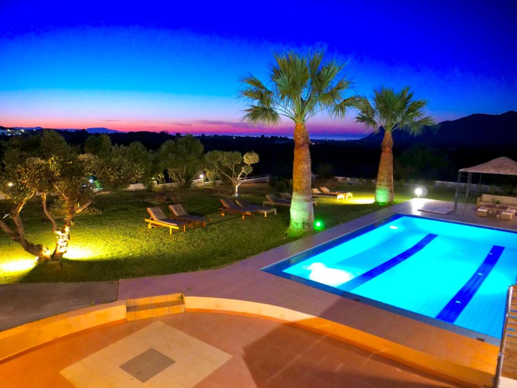 una piscina por la noche con palmeras en Villa Thamyris en Kalórrouma