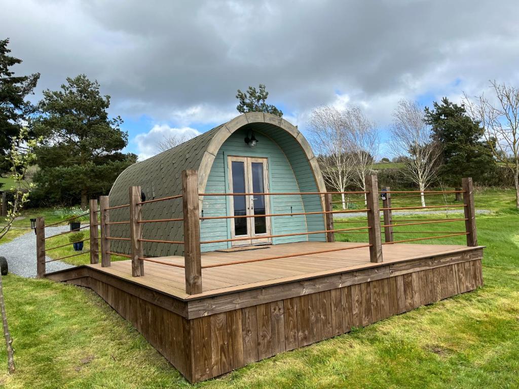 a small green dome house with a wooden deck at The Pod Patch - Trelerney Pod in Bishops Castle