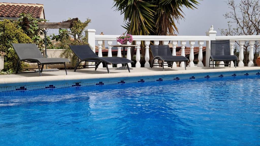 a row of chairs sitting next to a swimming pool at El Refugio in Turís