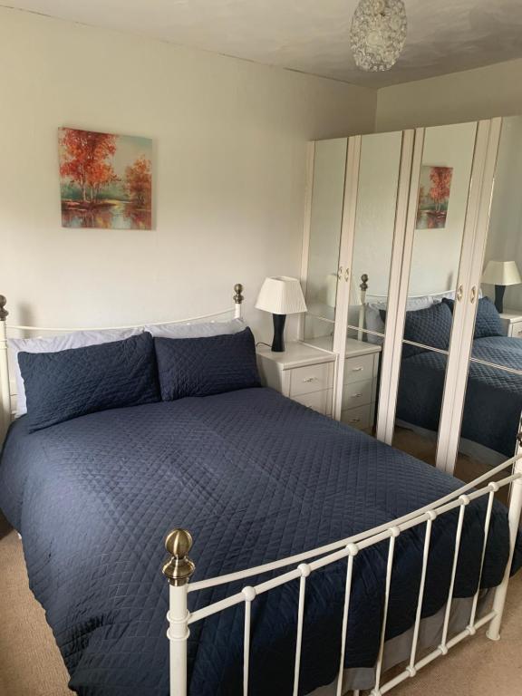 um quarto com uma cama com um edredão azul em Comfort Home em Wigan