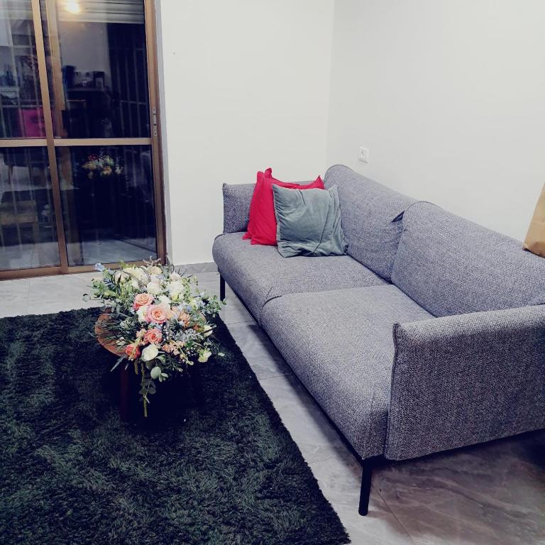 um sofá cinzento sentado numa sala de estar com um arranjo de flores em ירושלים של זהב em Jerusalém