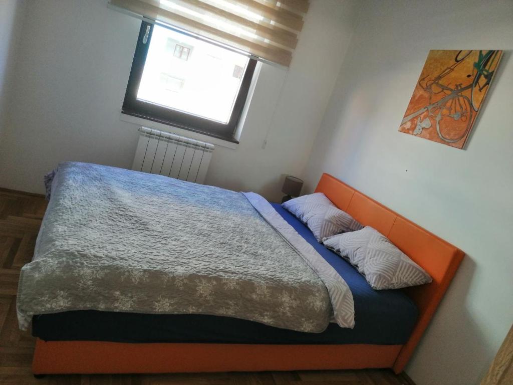 1 dormitorio con 1 cama con cabecero naranja y ventana en Apartman Nike, en Lukavica