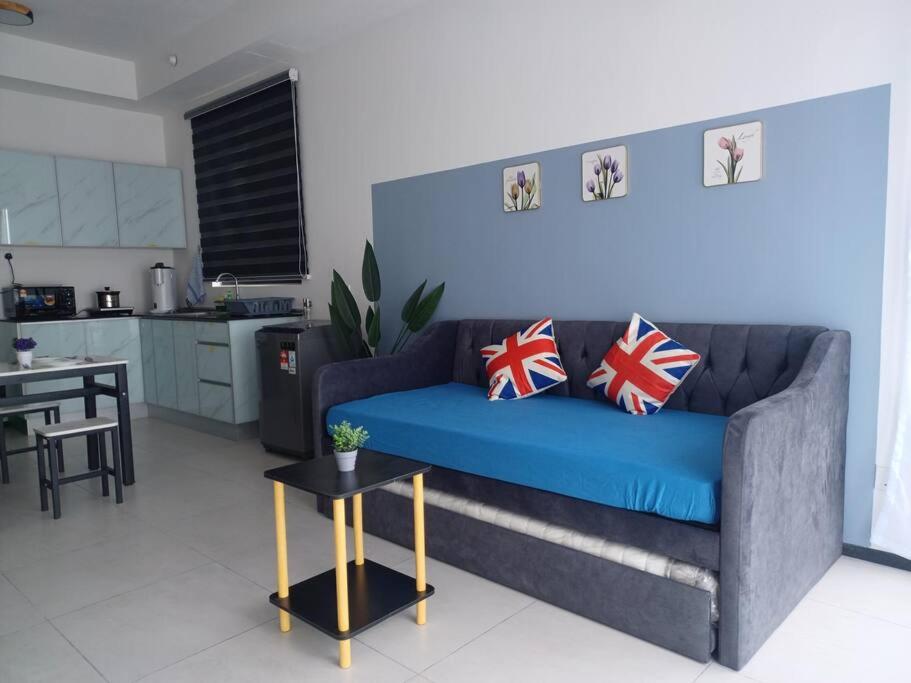 ein Wohnzimmer mit einem blauen Sofa und einer Küche in der Unterkunft Aesthetic 2BR @ Urban Suite (Infinite Pool & Gym) in Jelutong
