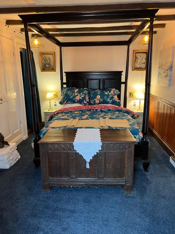 1 dormitorio con 1 cama grande con dosel de madera en Captain's Nook, Luxurious Victorian Apartment with Four Poster Bed and Private Parking only 8 minutes walk to the Historic Harbour en Brixham