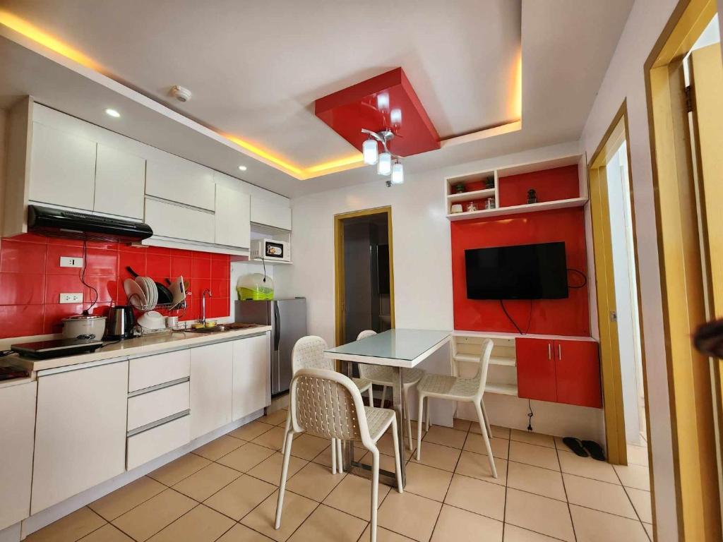 cocina con armarios rojos, mesa y sillas en JFive Homes @ 8Spatial_B2 en Davao