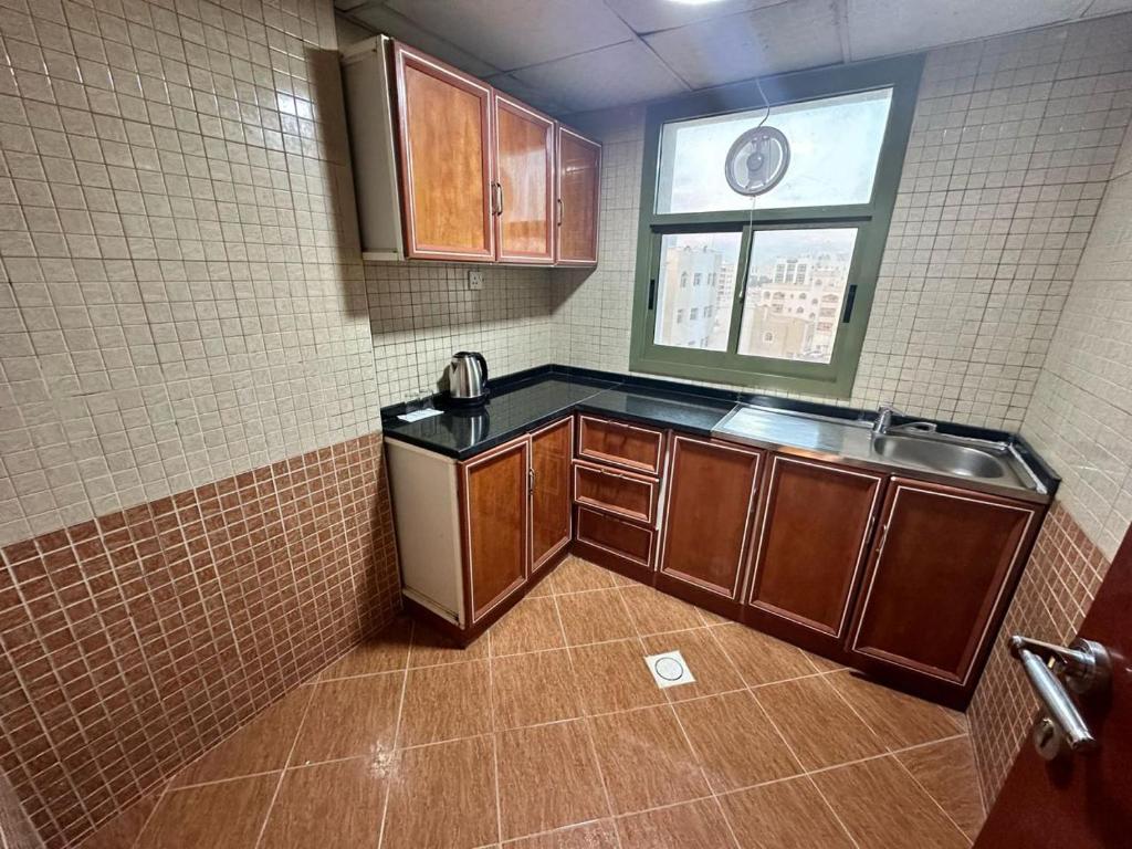 eine kleine Küche mit einem Waschbecken und einem Fenster in der Unterkunft Safari Hotel Apartments in Ajman 