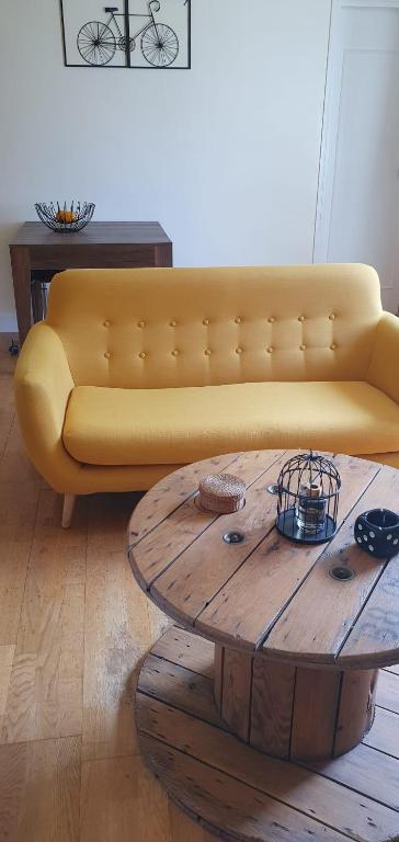 - un canapé jaune dans le salon avec une table basse en bois dans l'établissement Appartement F3 idéal JO proche de paris, à Épinay-sur-Seine